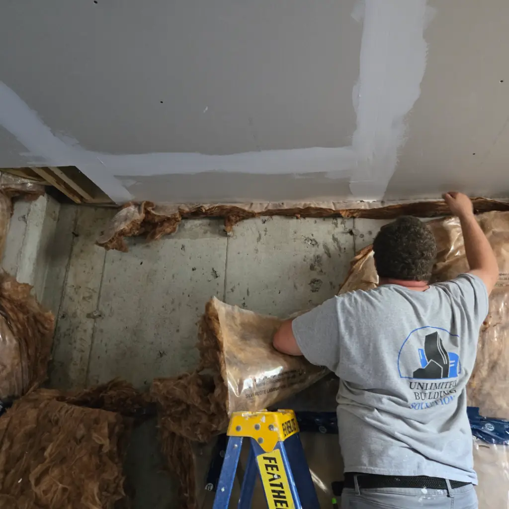 Water-affected basement insulation being removed to expose the concrete wall behind