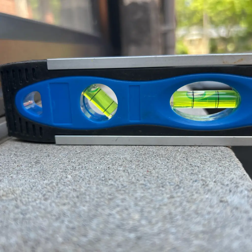 Spirit level checking a window sill for slope during a deficiency investigation