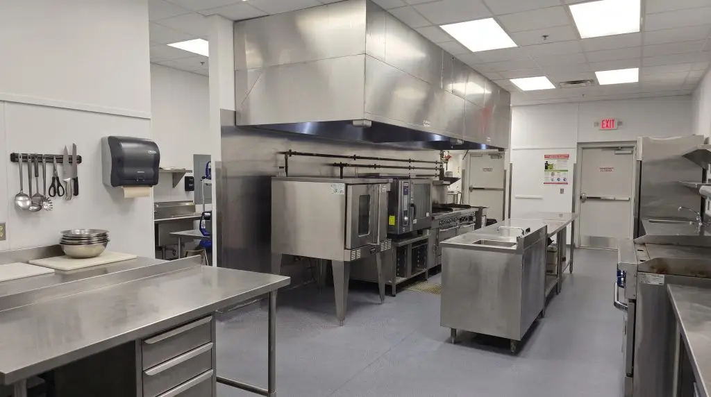 Completed commercial kitchen with stainless steel prep areas and extraction hood
