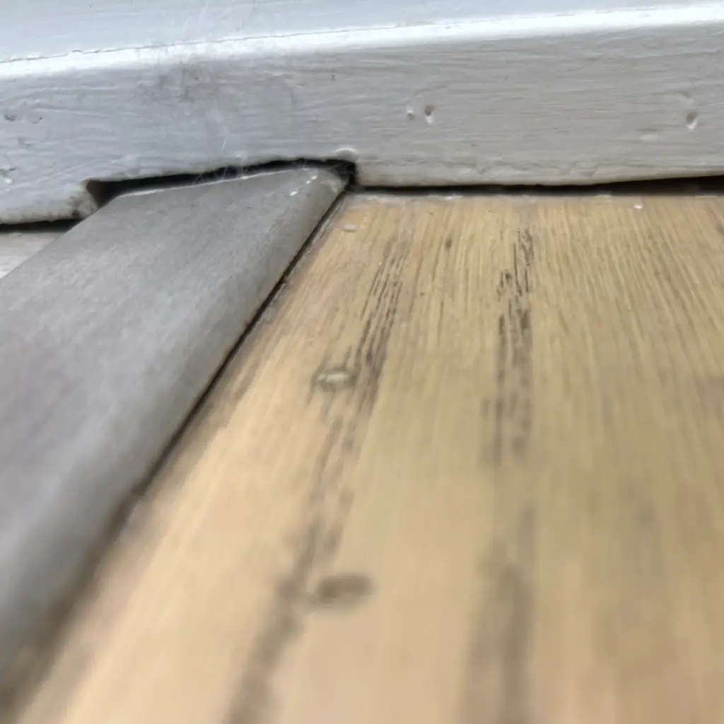 Lifted flooring at a threshold transition showing movement in a new-build home