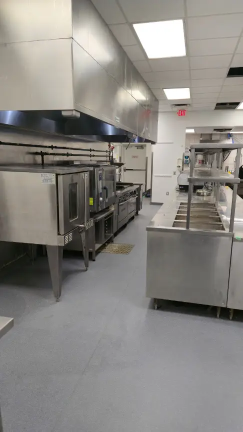 Renovated commercial kitchen with new epoxy flooring, extraction hood and stainless equipment line
