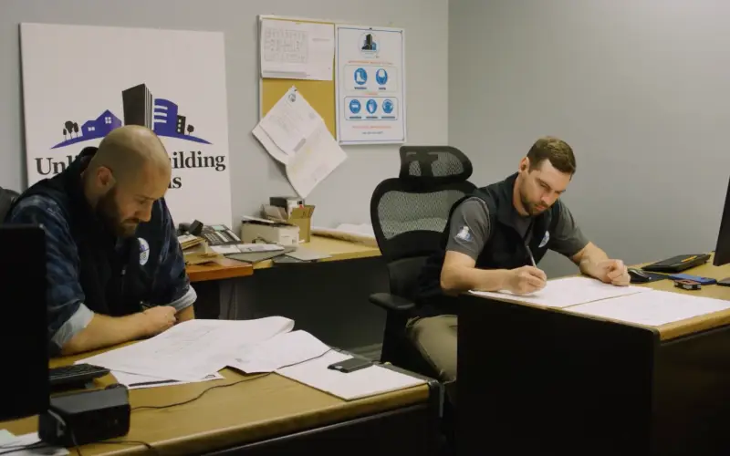 Two UBS project managers reviewing construction drawings at the Unlimited Building Solutions office